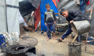 Duas crianças tentam limpar a sua tenda após chuvas intensas em dezembro de 2024 causarem inundações. Elas fazem parte de uma das inúmeras famílias deslocadas em Gaza, que enfrentam condições de vida difíceis. O CICV distribui artigos essenciais para ajudar a aliviar a sua situação.